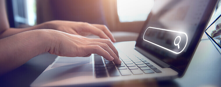 A person types a query into their home office laptop.