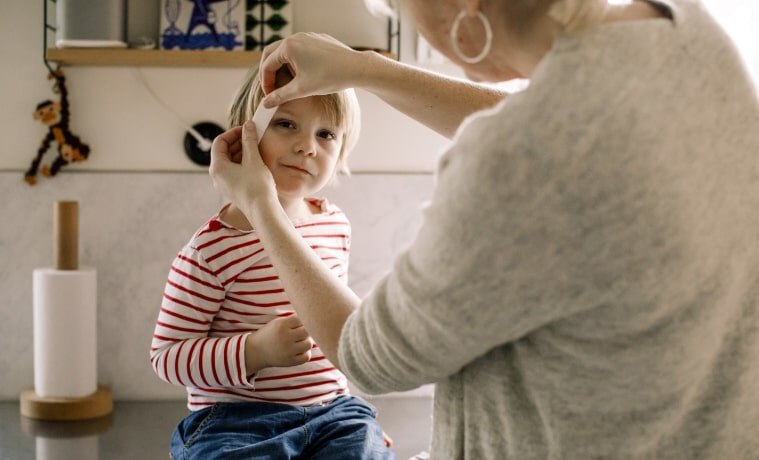 A woman applies a bandaid to a child.