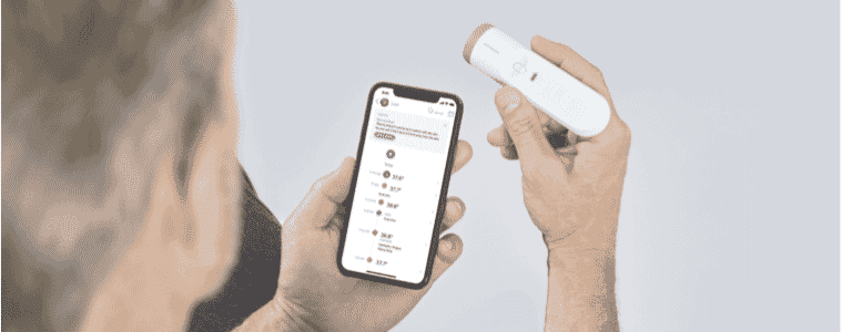 A man adds his temperature from the Withings Thermo Smart Temporal Thermometer
to his user profile on his smart phone.
