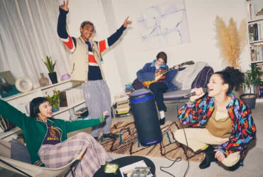 A group of young adults partying with a Sony Portable Part Speaker