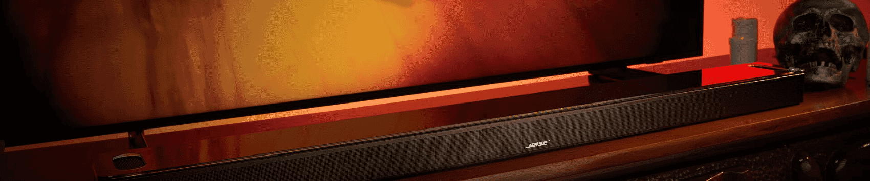 The Bose Ultra Soundbar on a TV unit in front of a TV