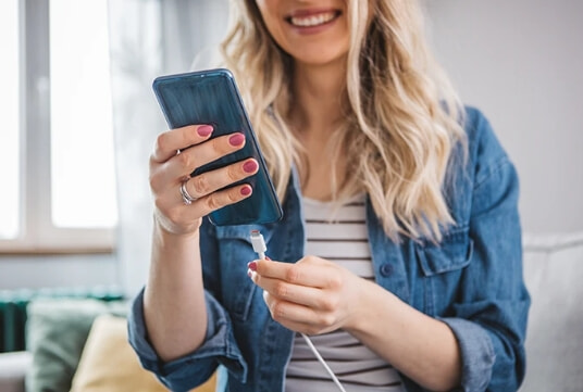 A woman plugs her phone into a GaN charger.