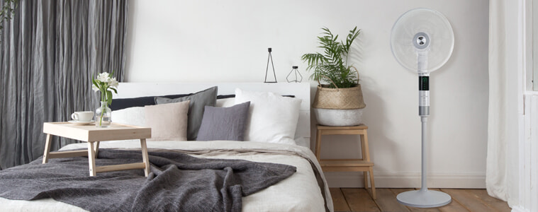The De'Longhi 360 Degree Pedestal Cooling Fan cools down a modern bedroom.