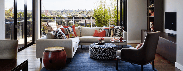 Modern lounge room with bright textiles and green views.